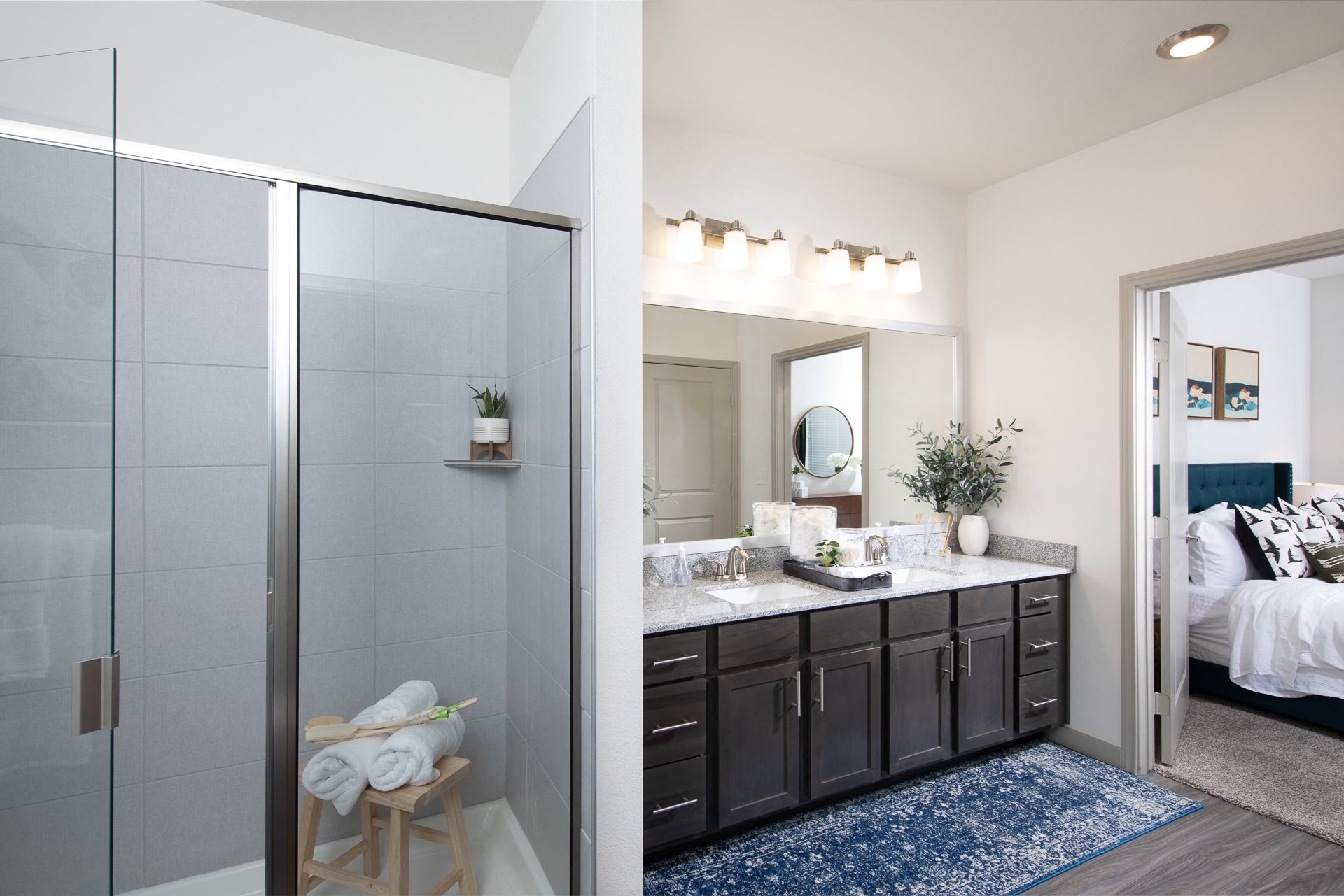 a bathroom with a glass walk-in shower and double sink at a senior apartment community